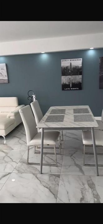 Large-format tile flooring with a neutral-toned veined pattern, accent wall featuring recessed ceiling lighting, and crisp white trim