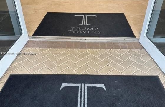 Entryway featuring glass-paneled double doors and herringbone-patterned stone paver flooring