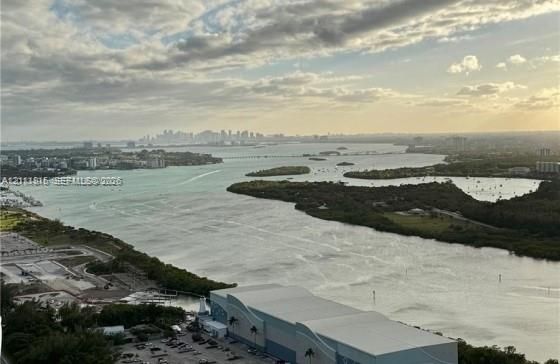 Panoramic bay and coastal skyline scenery featuring expansive water frontage, mangrove-lined shorelines, and distant urban horizon