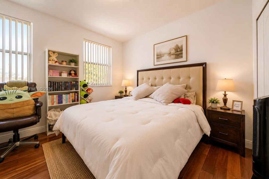 Bedroom featuring wood-finish flooring and multiple windows with vertical blinds