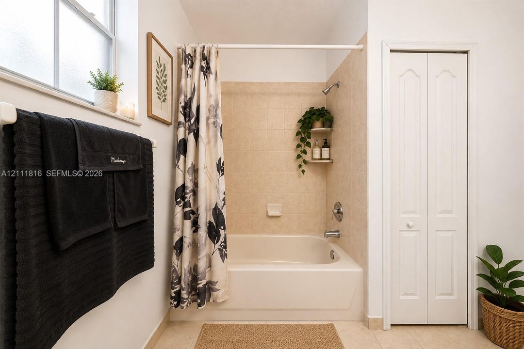 Full-size bathtub featuring tile surround, built-in shelving, chrome faucet fixtures, and an operable window