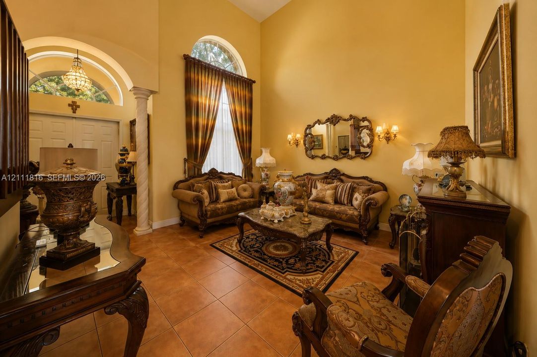 Vaulted ceiling, arched entryway with a decorative column, large arched window, and ceramic tile flooring