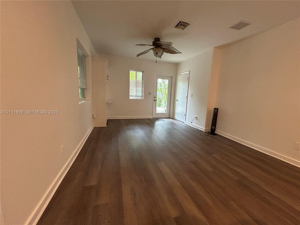Neutral interior featuring wood-finish flooring, ceiling fan, and exterior access door