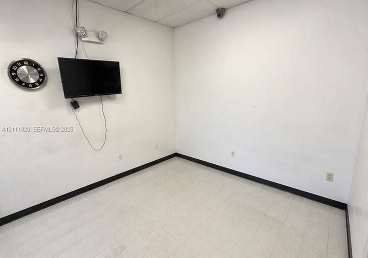 Interior space featuring white walls, drop ceiling tiles, light-colored tile flooring, and integrated security surveillance hardware