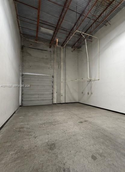 Industrial space featuring high ceilings with exposed metal decking, concrete flooring, steel roll-up door, and reinforced concrete wall construction