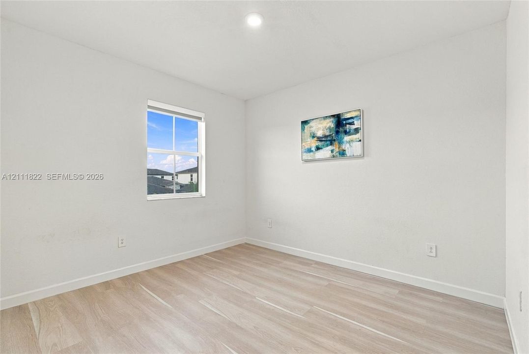 Neutral-toned interior space featuring wood-finish flooring, recessed lighting, and a single-pane window