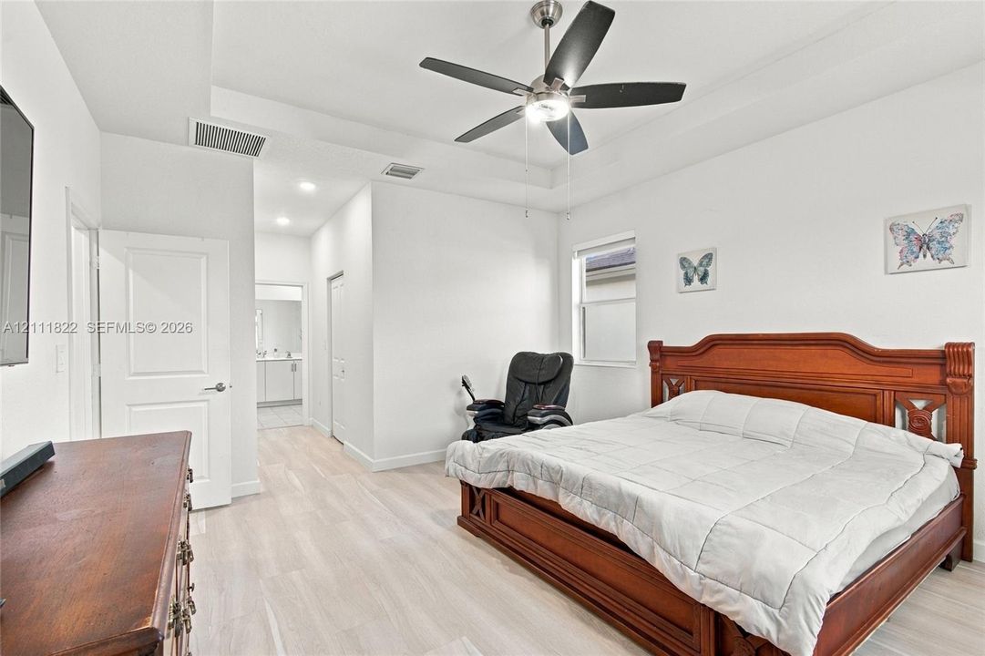 Interior space featuring wood-finish flooring, a tray ceiling, and a ceiling fan with integrated lighting