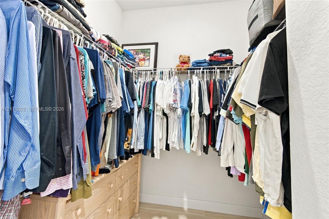Walk-in closet featuring multi-tiered wire shelving and integrated wood-finish cabinetry
