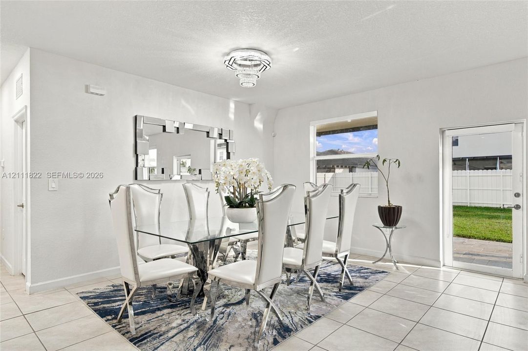 Bright interior featuring ceramic tile flooring, a multi-tiered crystal-style chandelier, and a glass-paneled exterior door providing natural light