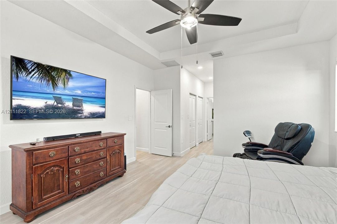 Tray ceiling, recessed lighting, wood-finish flooring, and ceiling fan with integrated light fixture
