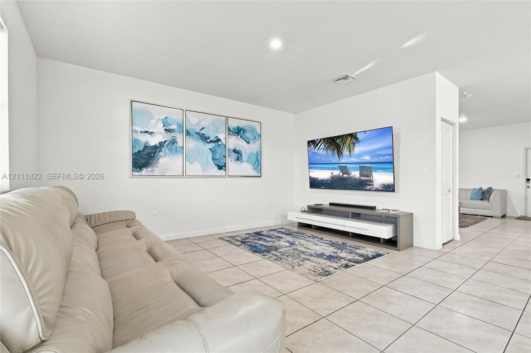 Living area featuring neutral-toned tile flooring, recessed lighting, and a crisp, white color palette