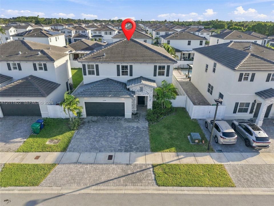 Two-story residence with a concrete tile roof, stone veneer facade accents, a paved driveway, and shutters