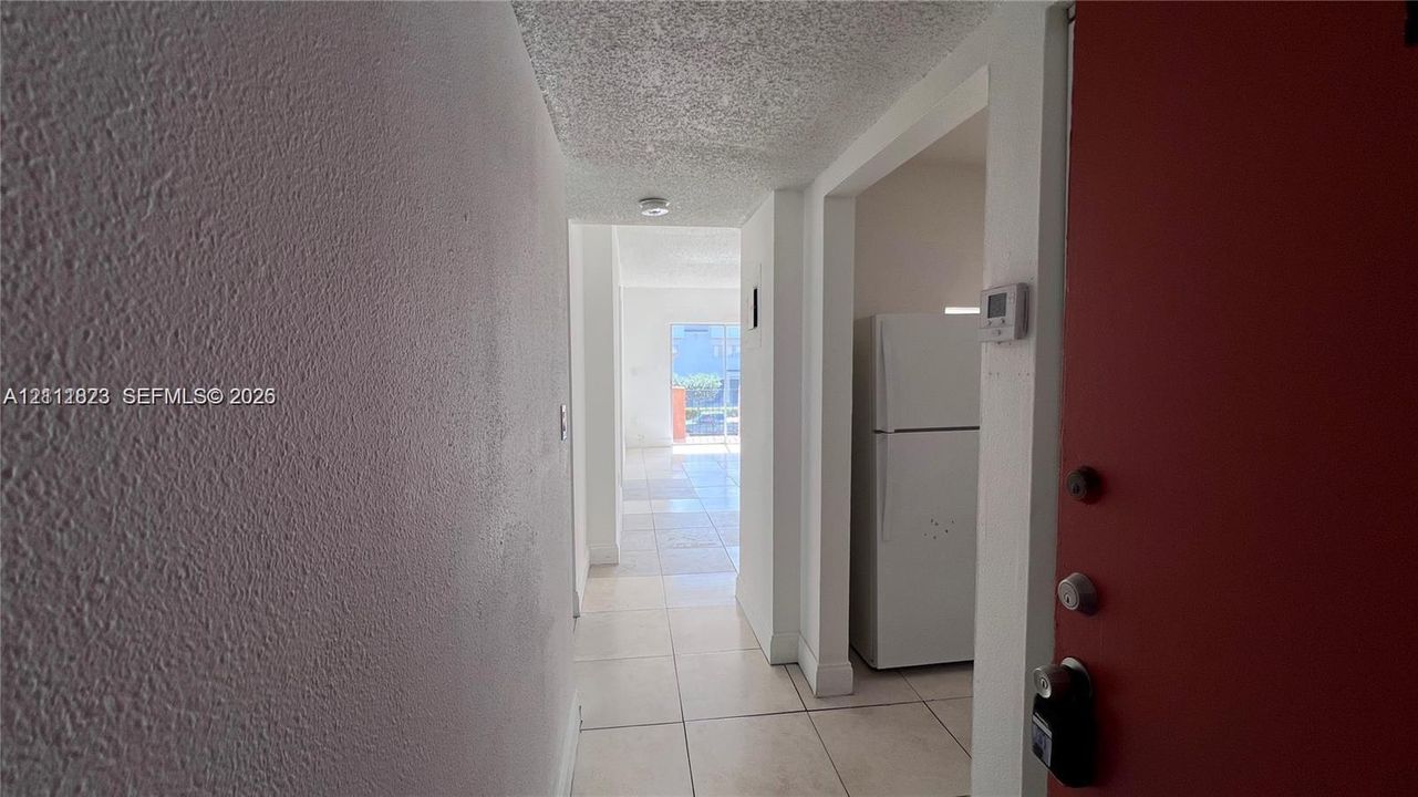 Entryway featuring light-toned tile flooring, textured ceilings, and a built-in refrigerator