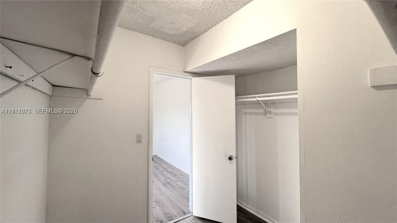Storage area featuring ceiling-height shelving, dual rod-and-shelf systems, and interior door access