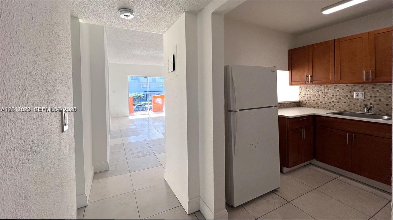Kitchen featuring wood cabinetry, mosaic tile backsplash, solid surface countertops, and tiled flooring