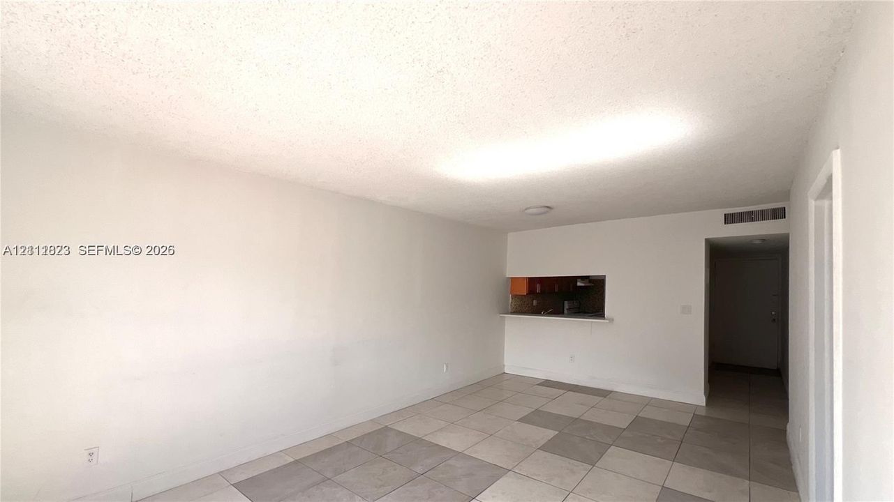 Interior space featuring white walls, square tile flooring in a checkerboard pattern, and a built-in pass-through window with an attached counter ledge