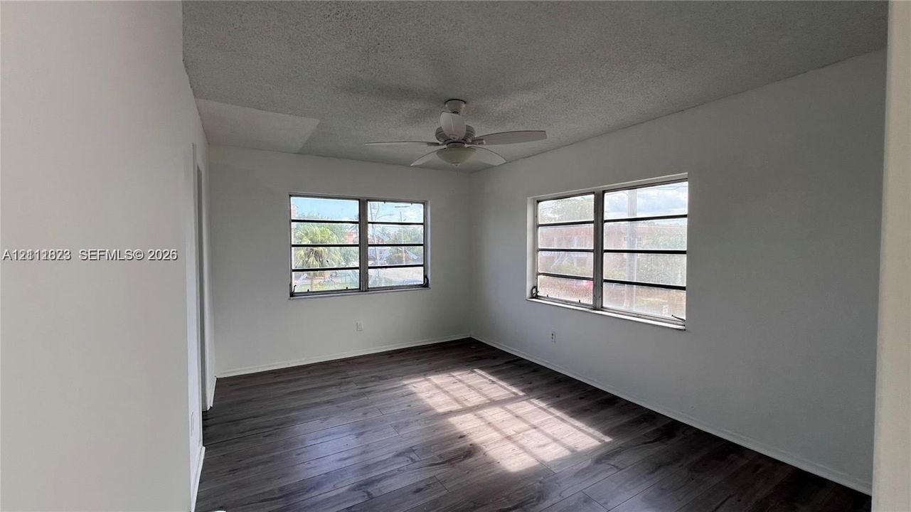 Interior space featuring wood-finish flooring, two multi-pane windows, and a central ceiling fan with integrated lighting
