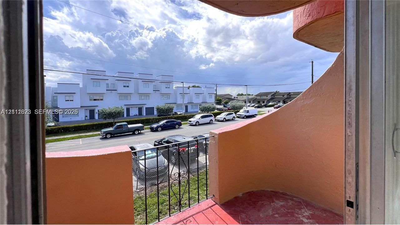Covered balcony featuring curved stucco walls and iron railings