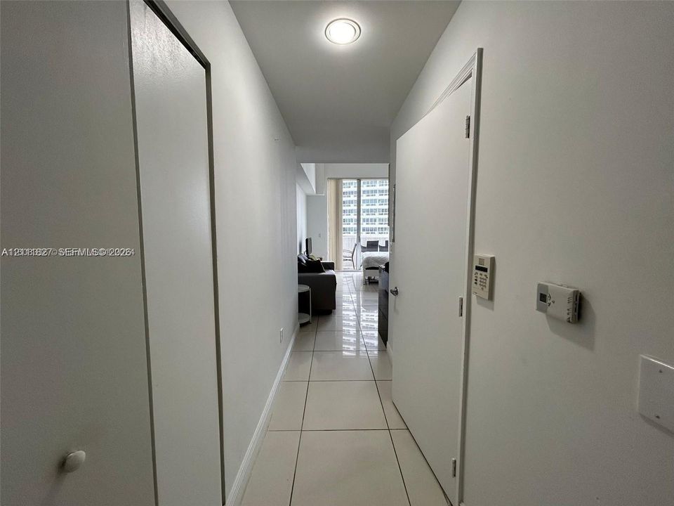 Hallway featuring large-format tile flooring, flush-mount ceiling lighting, and multiple interior doors with metal hardware