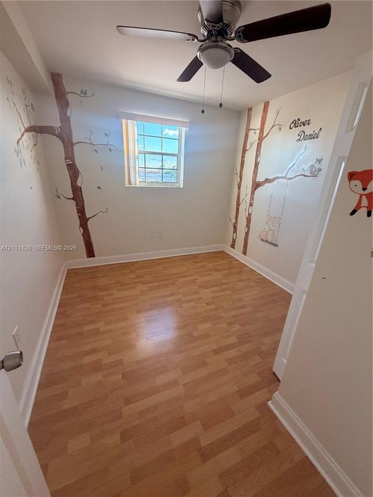 Interior room featuring wood-finish flooring, a multi-pane window, and a central ceiling fan with integrated lighting