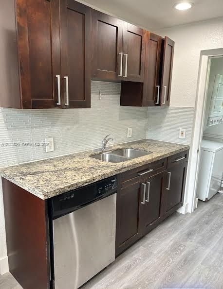 Dark-toned shaker cabinetry with brushed nickel hardware, stone-patterned countertop, stainless steel dishwasher, dual-basin stainless steel sink, and horizontal glass-tile backsplash