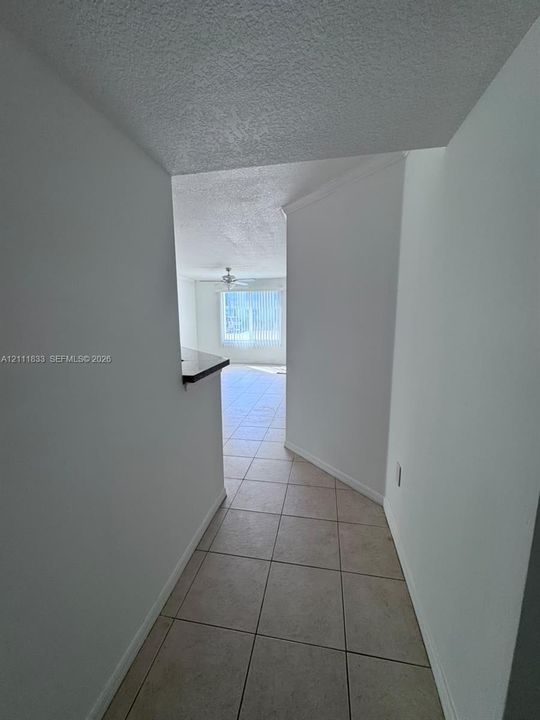 Neutral-toned ceramic tile flooring, built-in breakfast bar, ceiling fan, and window with vertical blinds