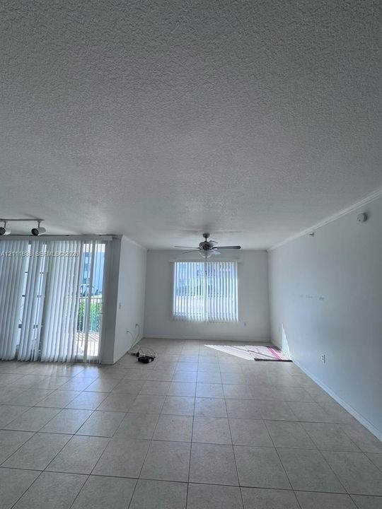 Interior space featuring large-format tile flooring, textured ceiling, ceiling fan with light kit, vertical window blinds, and adjustable track lighting