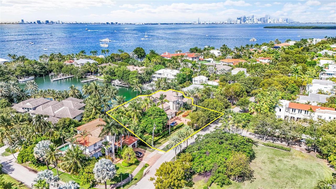 Aerial perspective of waterfront property featuring mature landscaping, paved driveway, and proximity to open water