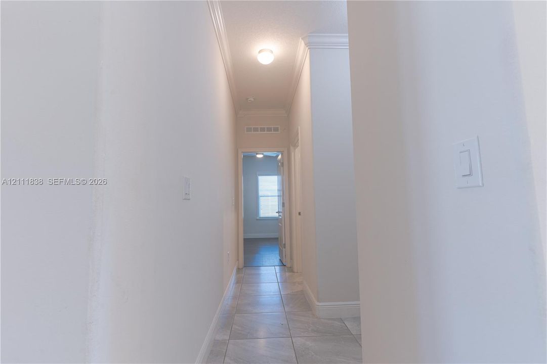 Hallway featuring tile flooring, crown molding, and a flush-mount ceiling light