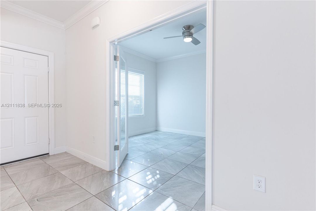 Interior space featuring polished tile flooring, crown molding, French doors with glass panes, and a ceiling fan with integrated lighting
