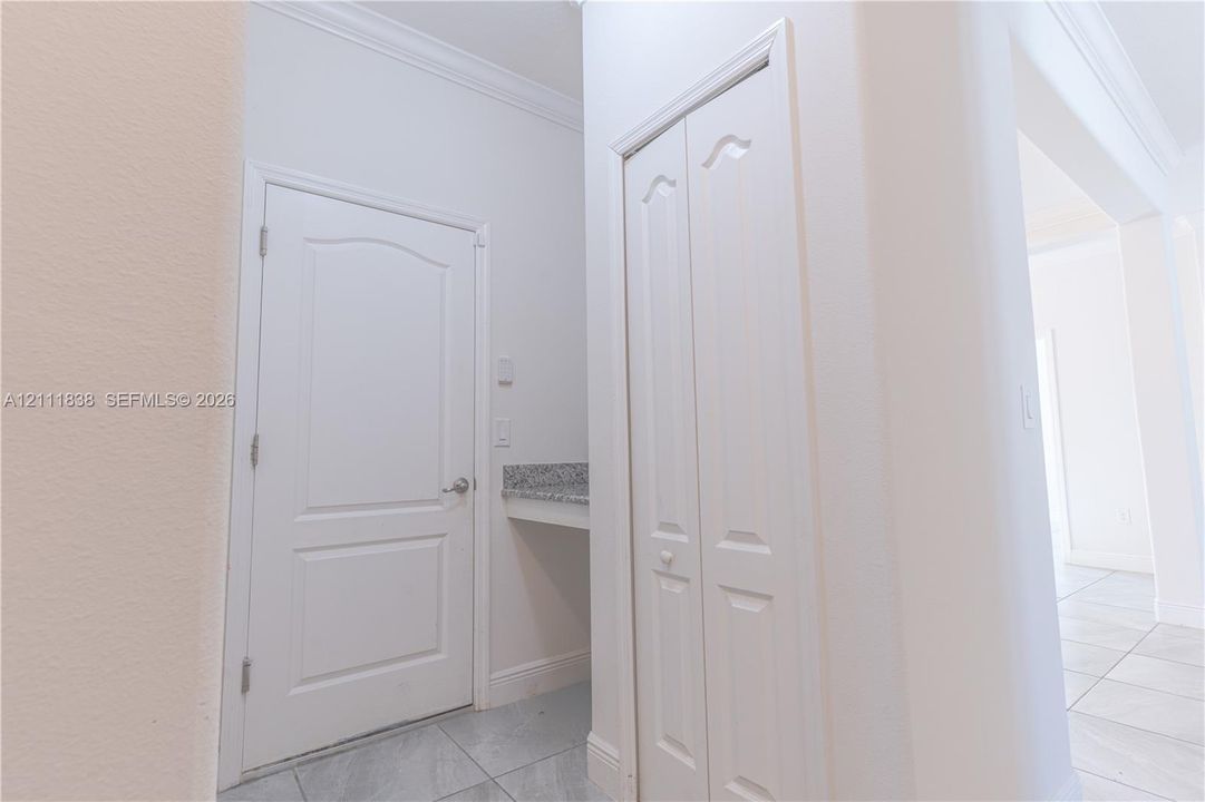 Interior entryway featuring tile flooring, a six-panel door, built-in recessed counter with stone surface, and bi-fold closet doors