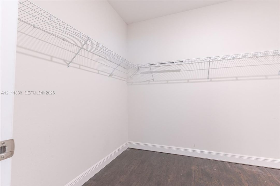 Storage area featuring neutral wall paint, wood-finish flooring, and multi-tiered wire shelving