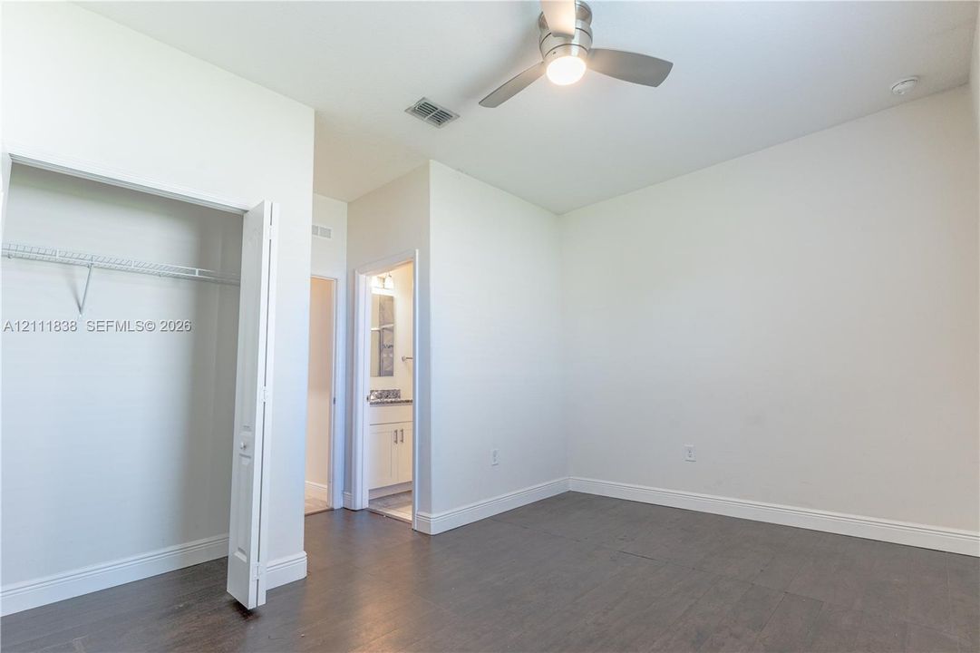 Room featuring wood-finish flooring, a ceiling fan with integrated lighting, and a closet with wire shelving