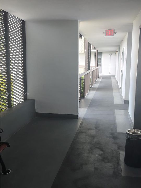 Covered exterior corridor featuring painted concrete flooring and decorative metallic lattice privacy screening