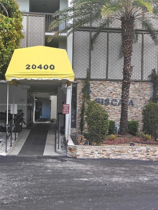 Building exterior featuring stone masonry facade, decorative metal screening, concrete access ramp, and metal awning