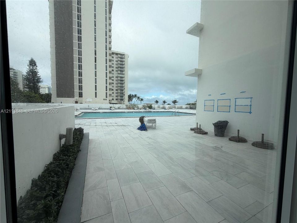 Expansive stone-paved terrace featuring a swimming pool, integrated landscaping, and solid masonry privacy walls