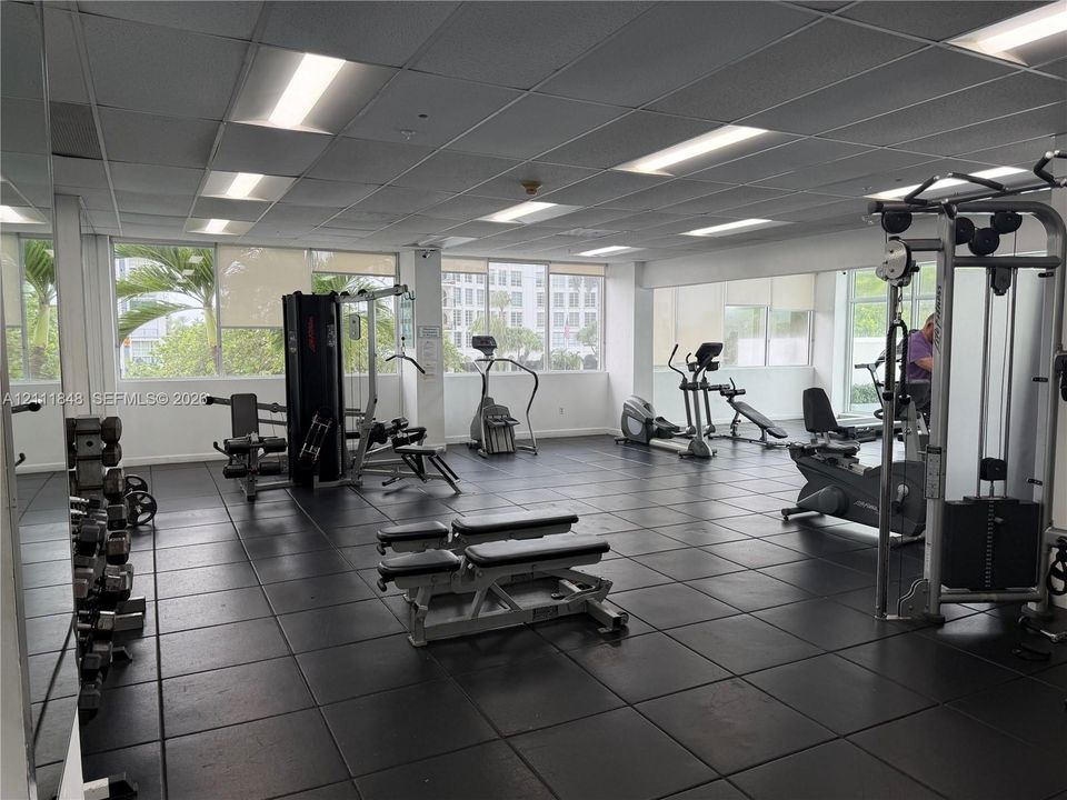 Fitness center featuring rubber flooring, drop ceiling with recessed lighting, and expansive windows