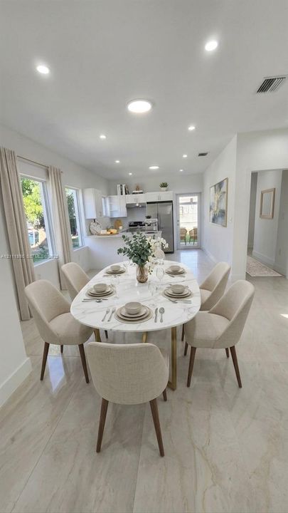 Open-concept interior featuring large-format tile flooring, recessed lighting, and kitchen cabinetry with a peninsula