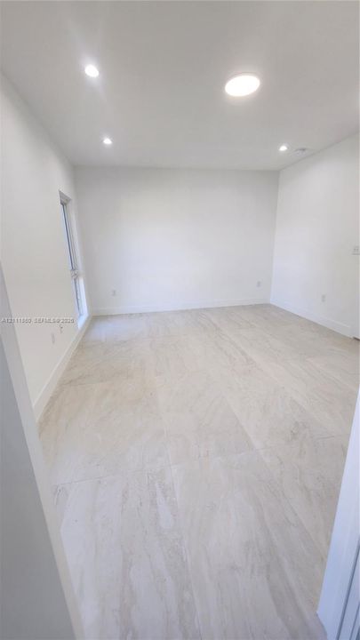 Large-format tile flooring, recessed ceiling lighting, and neutral wall tones