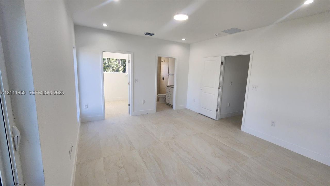 Interior space featuring neutral wall tones, large-format tile flooring, recessed ceiling lighting, and multiple interior paneled doors