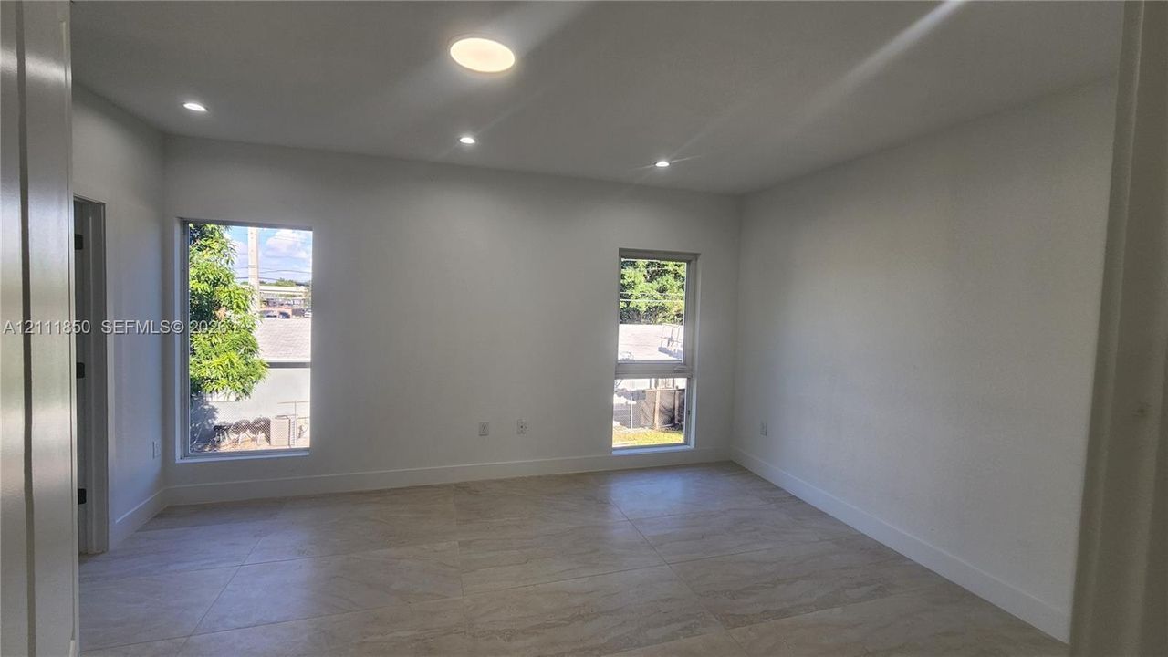Interior space featuring large-format tile flooring, recessed ceiling lighting, and dual windows with exterior visibility