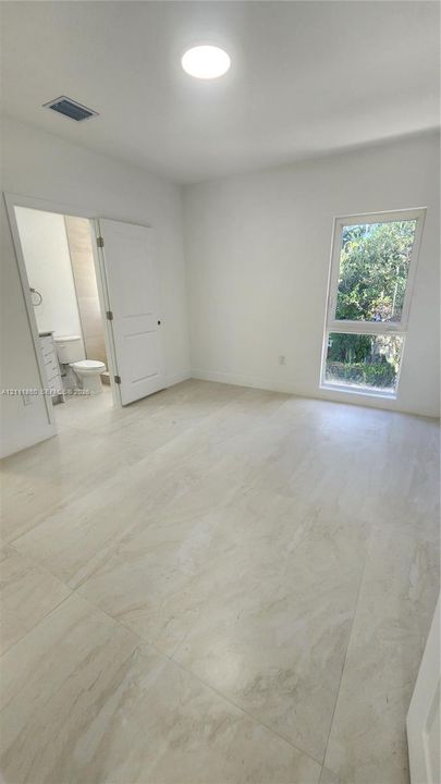 Neutral-toned tile flooring, recessed ceiling lighting, and a single-pane vertical window
