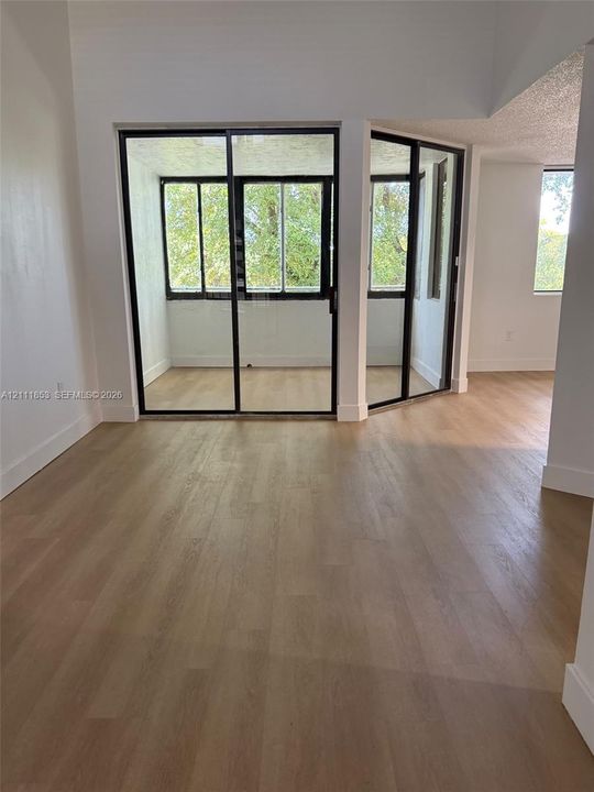 Wood-finish flooring throughout, floor-to-ceiling glass sliding doors, and a glass-enclosed interior balcony