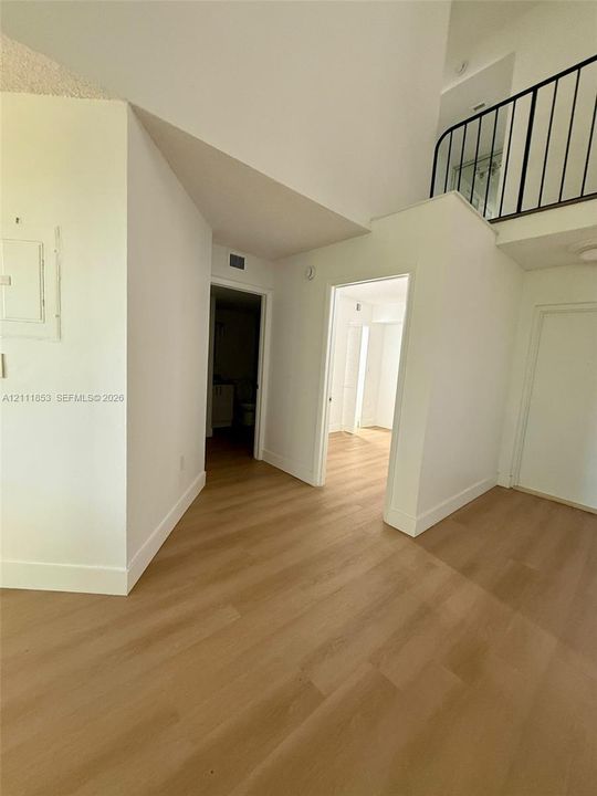 Interior space featuring high ceilings, wood-finish flooring, and a metal staircase railing