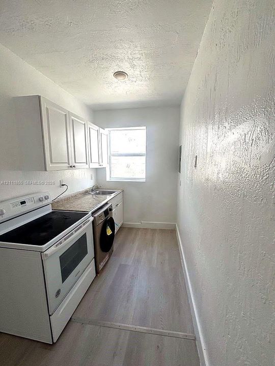 White cabinetry, stone-finish countertops, stainless steel sink, electric range, and wood-finish flooring