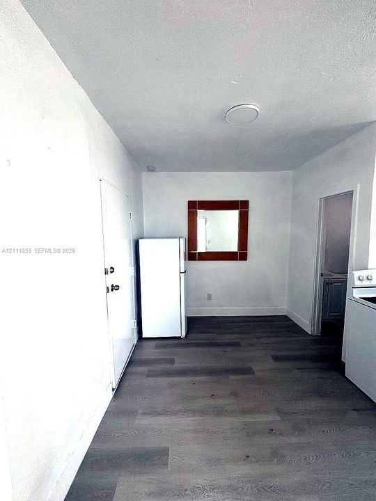 Interior space featuring wood-finish flooring, white walls, and a ceiling-mounted light fixture