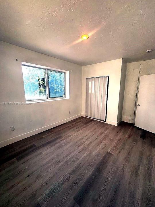 Room featuring wood-finish flooring, a dual-pane window, and a built-in accordion-style closet door
