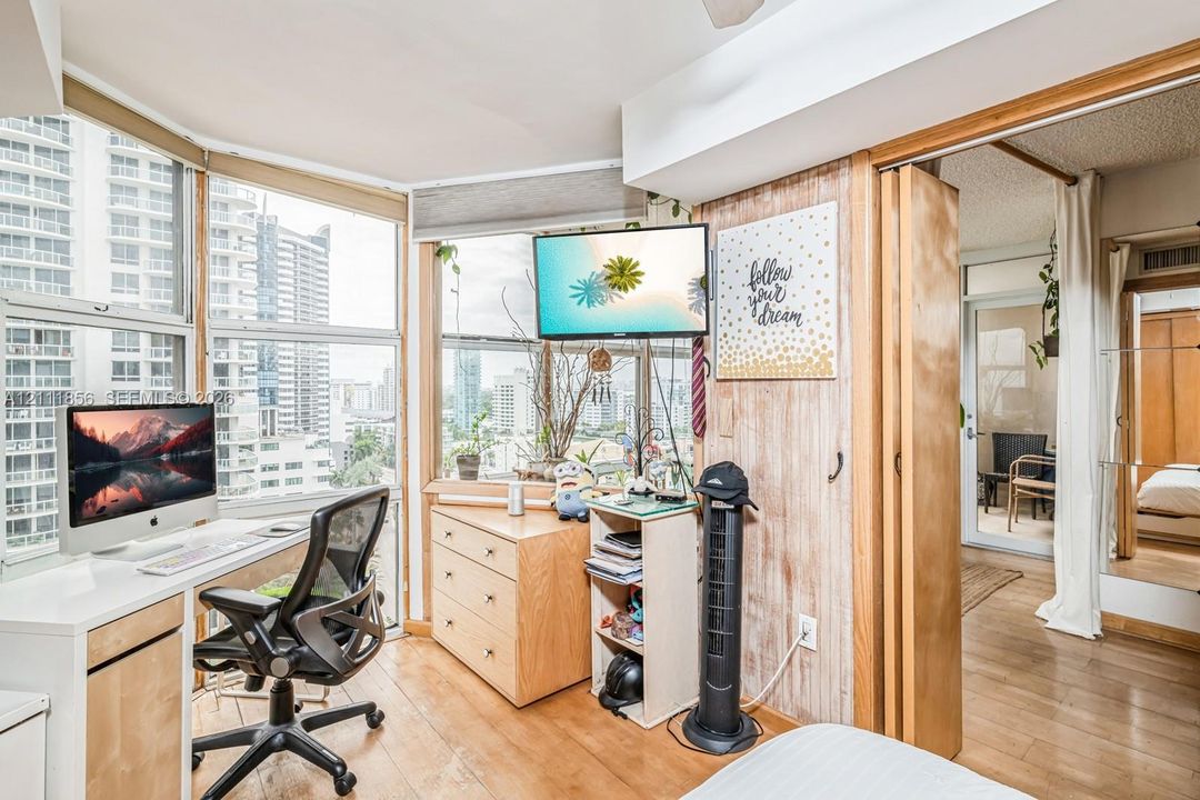 Floor-to-ceiling windows with urban exposure, wood-finish flooring, and wood-paneled accent wall