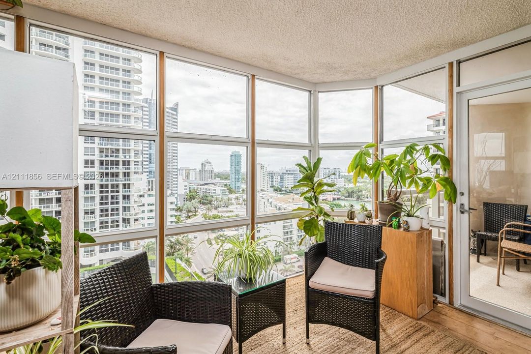 Enclosed balcony featuring floor-to-ceiling windows with panoramic urban exposure and a glass-paneled door