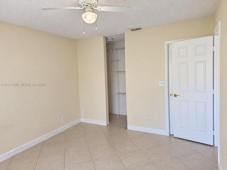 Interior space featuring diagonal tile flooring, a ceiling fan with integrated lighting, and a six-panel door